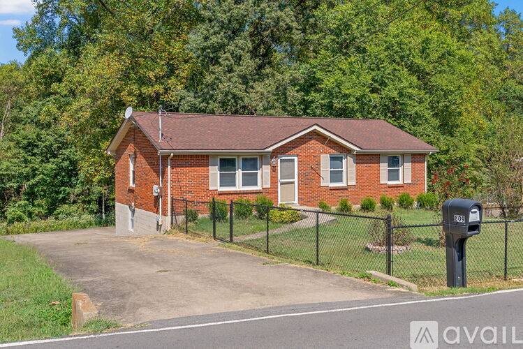 A red brick house with a black fence and a mailbox in front.