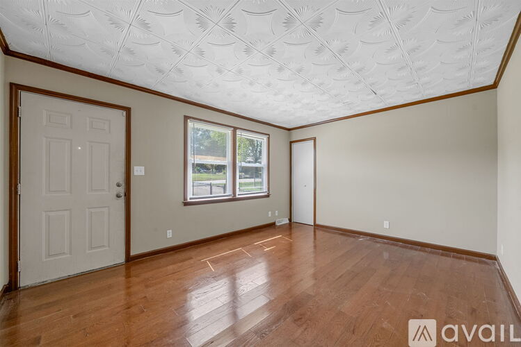 A room with wooden floors and a window with a view of trees.