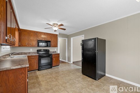 A kitchen with wooden cabinets and a black refrigerator.
