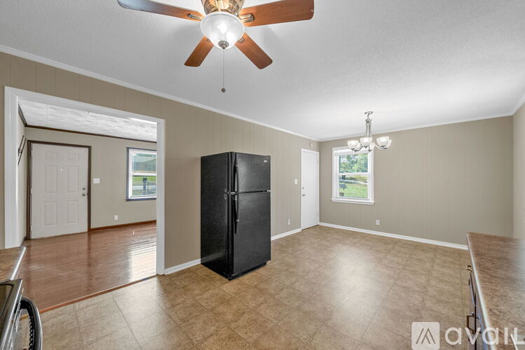 A spacious room with a black fridge and a ceiling fan.