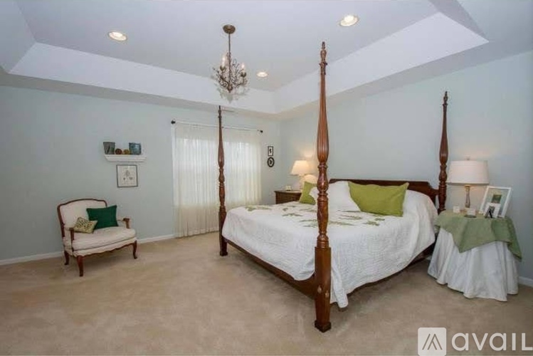 A bedroom with a large bed and a chair.
