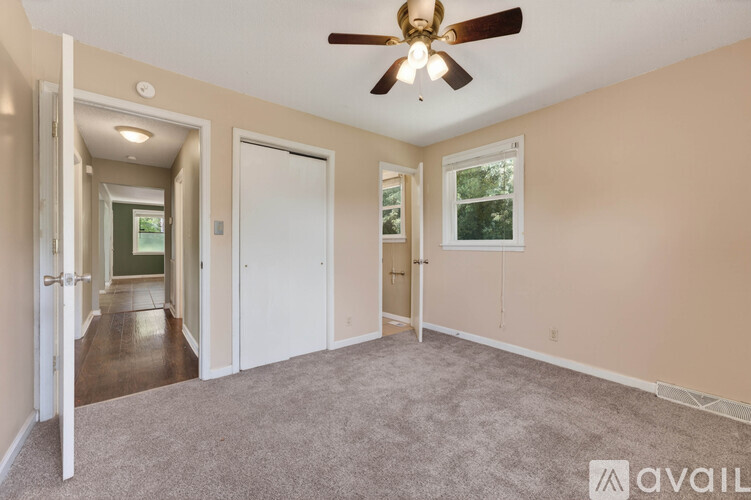 A spacious room with a ceiling fan and carpeted floor.