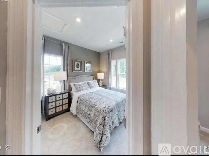 A bedroom with a large bed and a window with curtains.