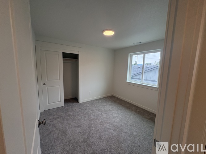 A room with a carpeted floor and a window with a view of a building outside.