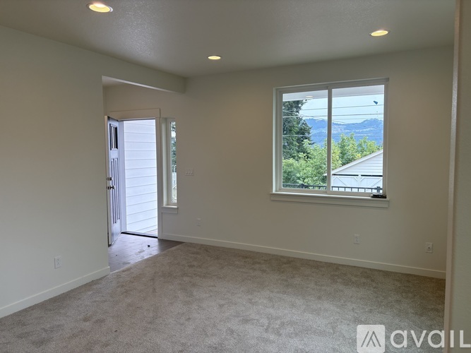 A spacious room with a window overlooking a residential area.
