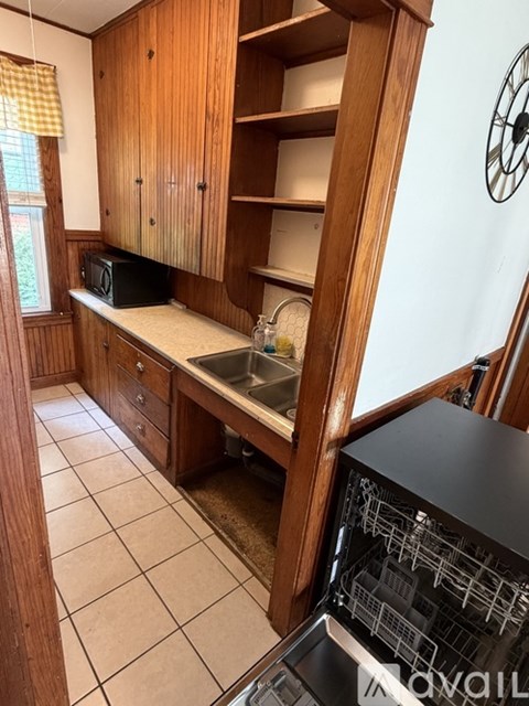 A kitchen with wooden cabinets and a black microwave.