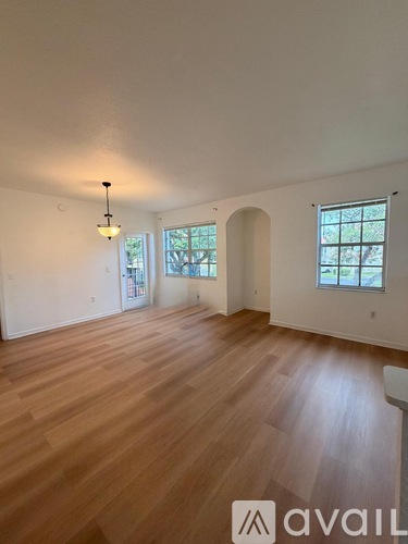 A room with wooden flooring and a chandelier hanging from the ceiling.