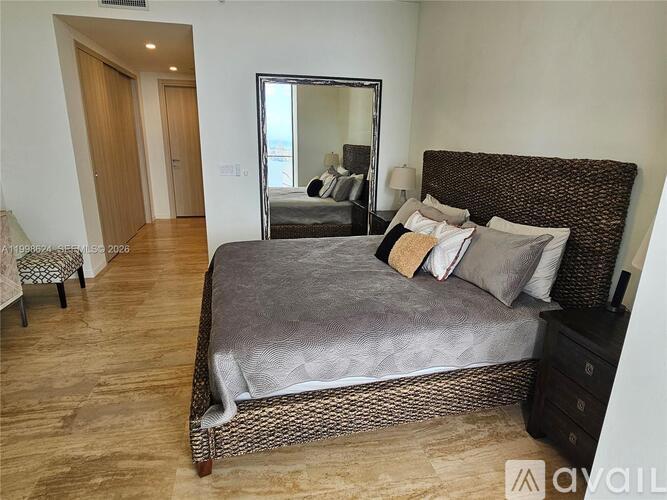 A bedroom with a large bed and a mirror on the wall.
