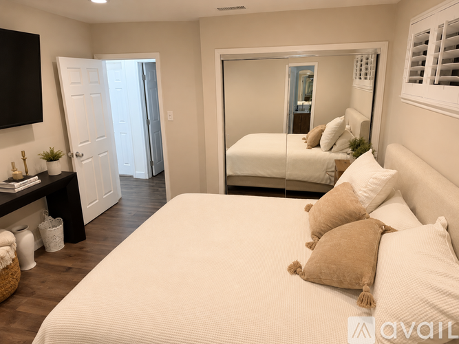 A bedroom with a large bed and a mirror on the wall.