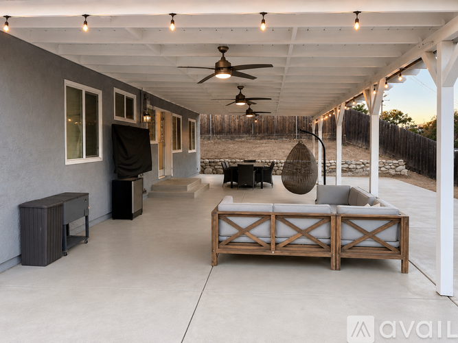 A modern outdoor living space with a wooden sofa and a ceiling fan.