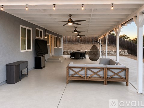 A modern outdoor living space with a wooden sofa and a ceiling fan.