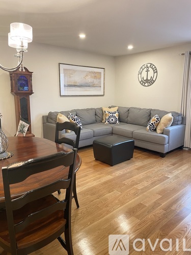 A living room with a grey couch, a wooden table, and a wooden chair.