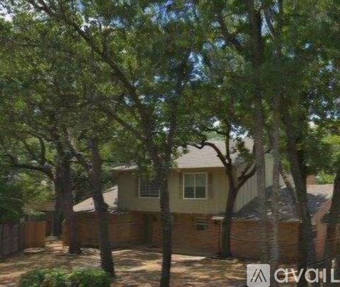 A house with a fence and trees in front of it.