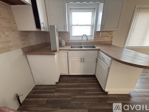 A kitchen with white cabinets and a window above the sink.
