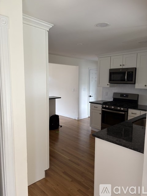 A kitchen with a black counter top and white cabinets.