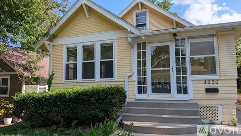 A yellow house with a white door and windows.