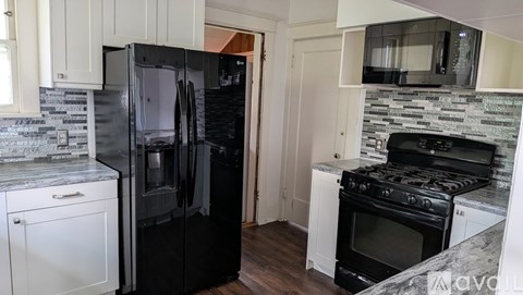A kitchen with black appliances and white cabinets.