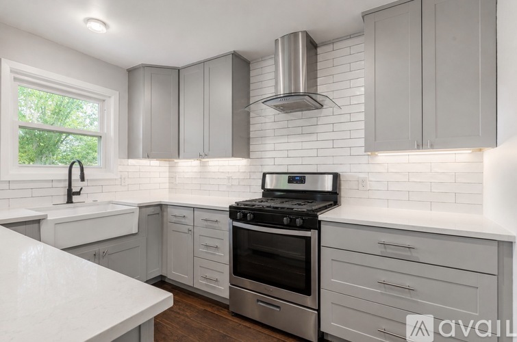 A kitchen with white cabinets and a stainless steel range hood.