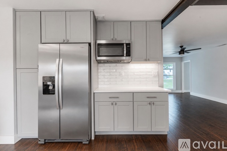A kitchen with a stainless steel refrigerator and white cabinets.