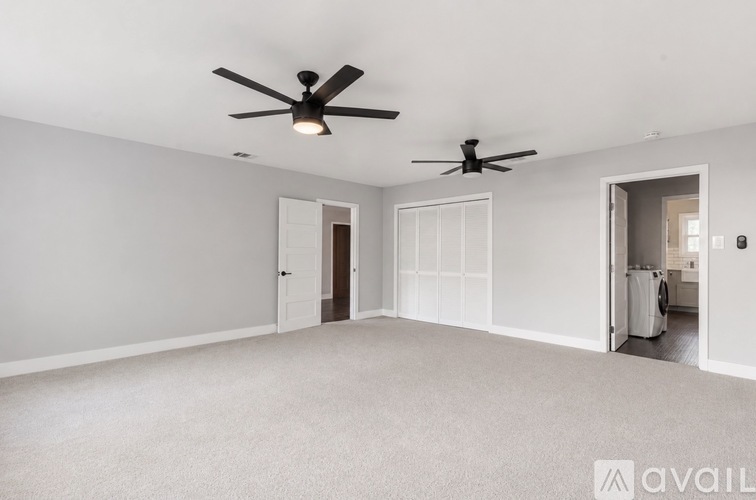 A spacious room with two ceiling fans and a carpeted floor.