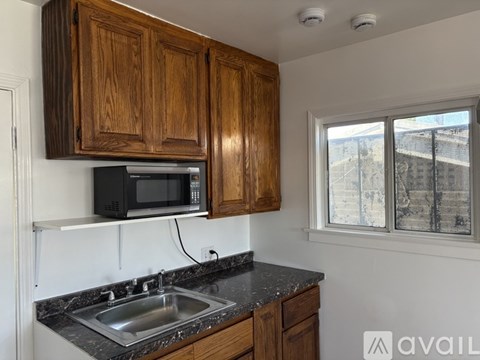 A kitchen with wooden cabinets and a black microwave oven.