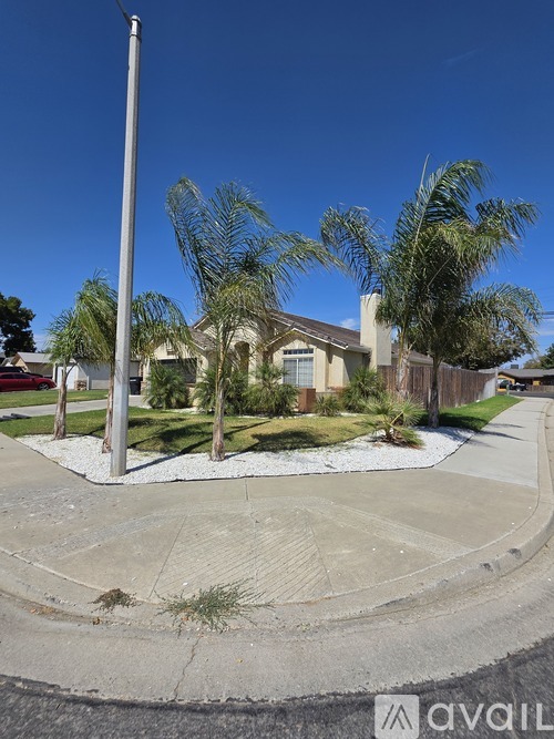 A house with a driveway and palm trees in front.