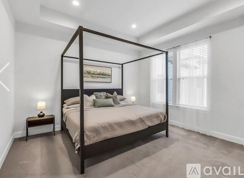 A bedroom with a four poster bed, a nightstand with a lamp, and a painting on the wall.