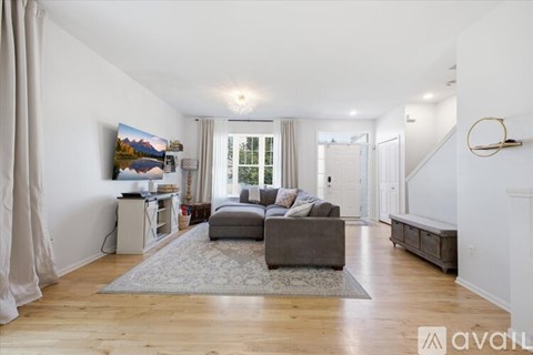 A living room with a grey couch and a painting on the wall.