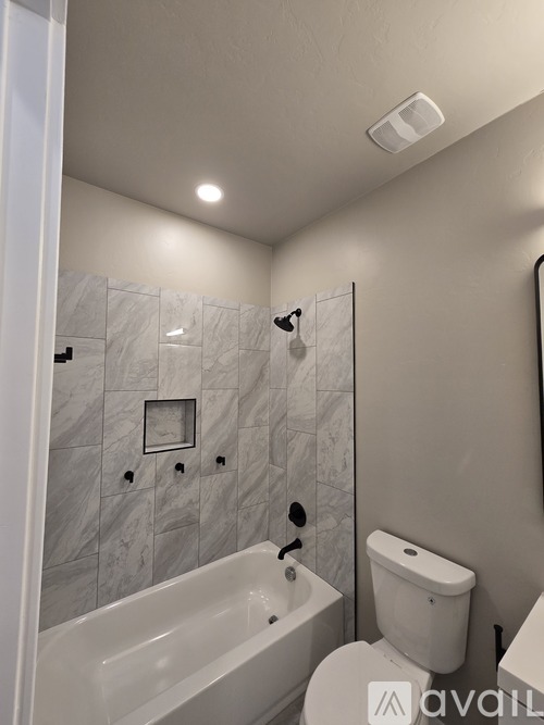 A spacious room with a ceiling fan and lighting fixtures.