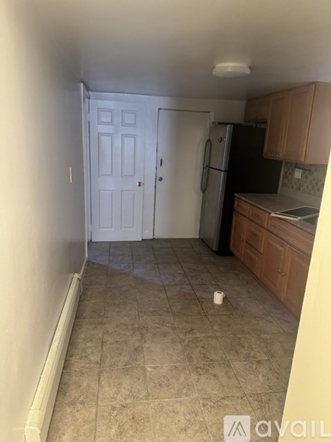 A kitchen with a refrigerator, cabinets, and a door.