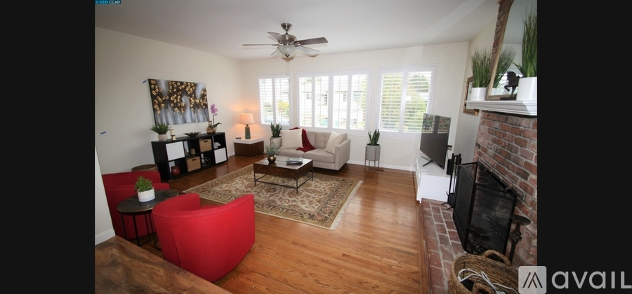 A living room with a red chair and a fireplace.