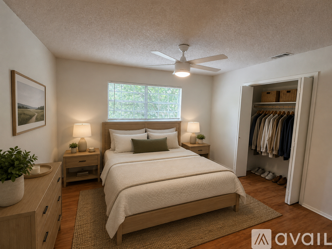 A bedroom with a large bed, a ceiling fan, and a window with a view of trees.