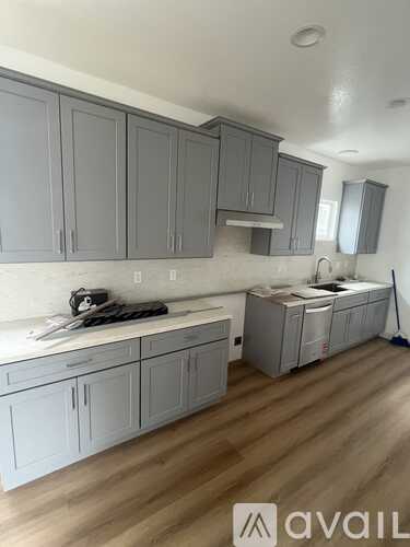 A kitchen with grey cabinets and a white countertop.