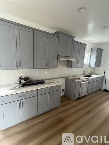 A kitchen with grey cabinets and a white countertop.