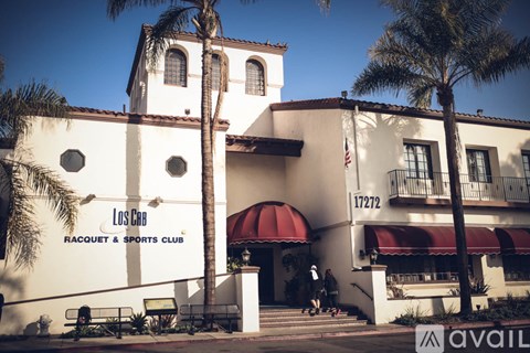 A white building with a red awning and a sign that says Los Caballos Racquet & Sports Club.