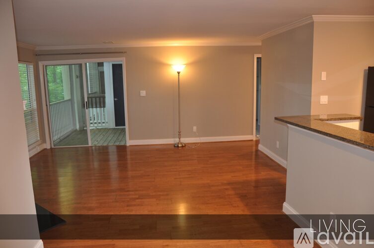A living room with a wooden floor and a lamp on the floor.