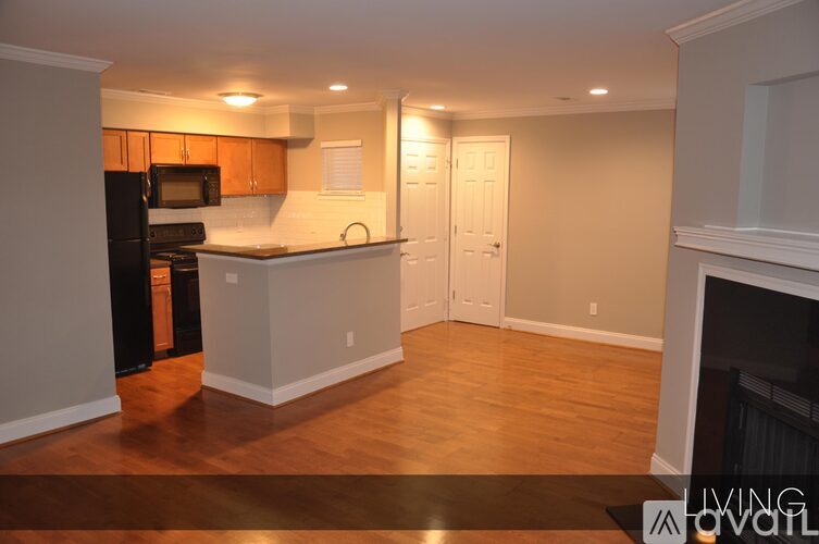 A kitchen with a black refrigerator and wooden cabinets.