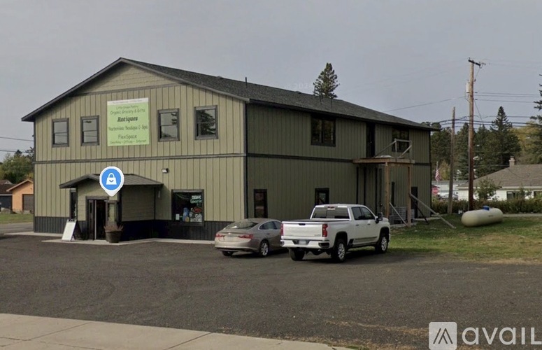A building with a blue sign on the front and a white car parked in front.