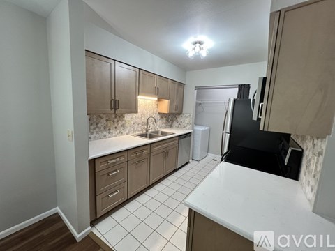 A kitchen with brown cabinets and a black refrigerator.