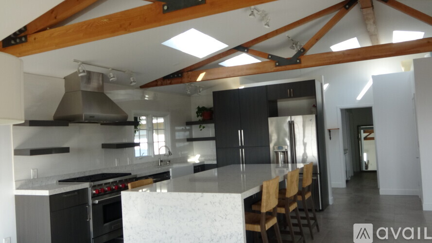 A modern kitchen with a large island and wooden beams on the ceiling.