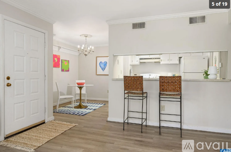 A white door is on the left of a room with a table and two chairs.