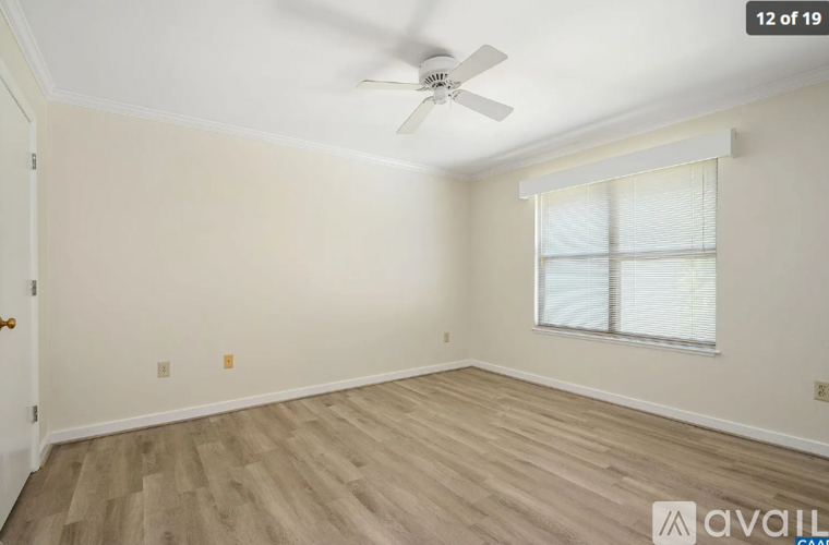 A room with a ceiling fan and a window with blinds.