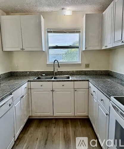 A kitchen with white cabinets and a window.