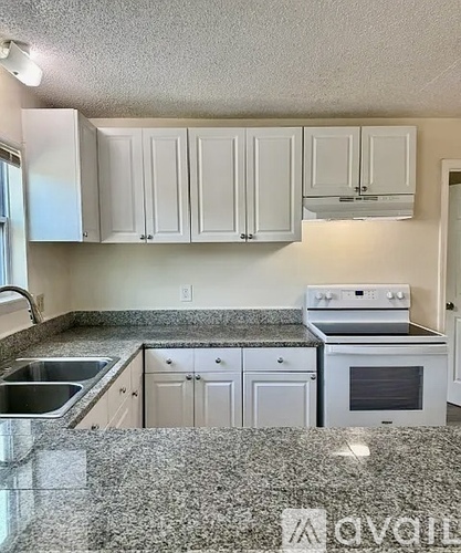A kitchen with granite countertops and white cabinets.