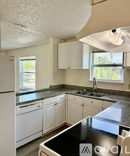 A kitchen with white cabinets and a black counter top.