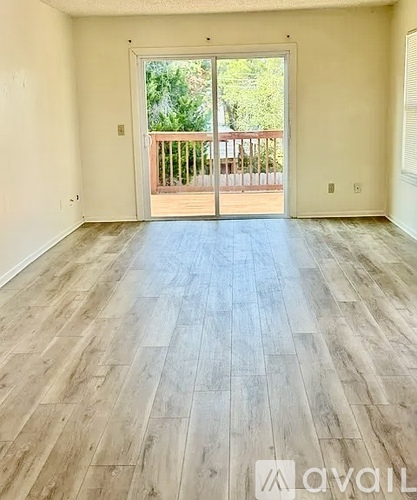 A room with wooden flooring and a sliding glass door leading to a balcony.
