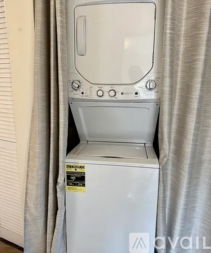 A white dryer is sitting in front of a curtain.