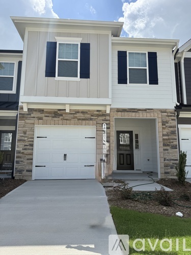 A two-story house with a garage door and a driveway.