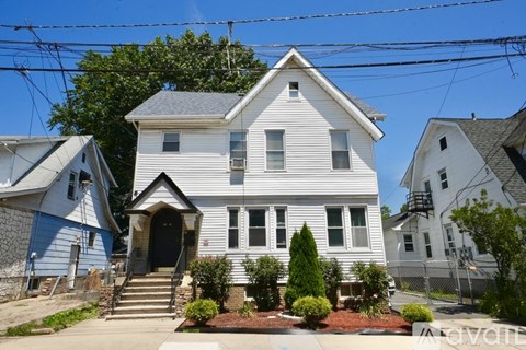 A white house with a grey roof and a small front yard.