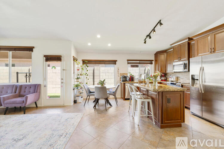 A kitchen with a refrigerator, sink, and dining table with chairs.